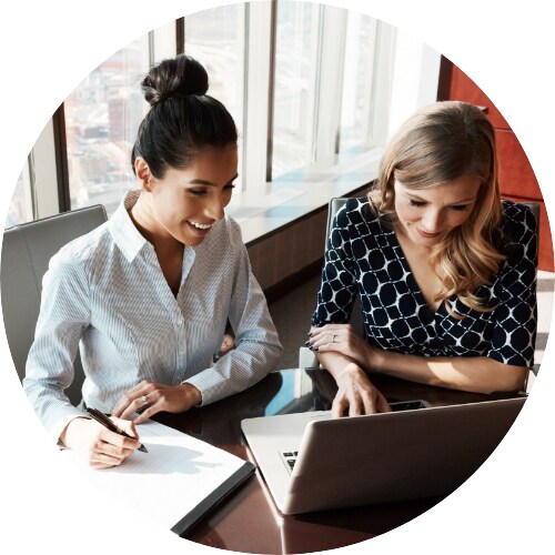 Two businesswomen working together on a laptop in an office.
